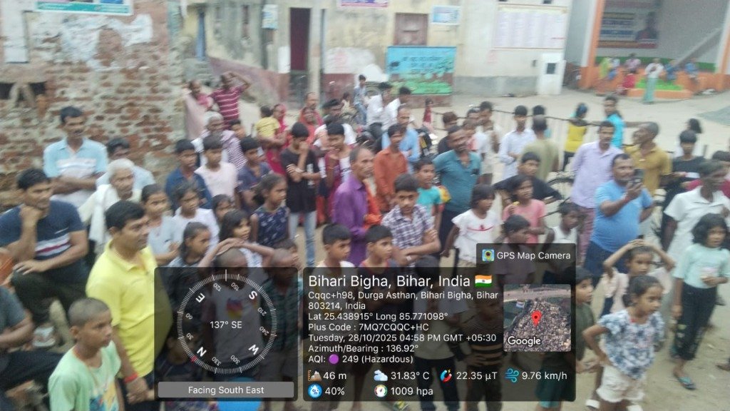 Village assembly crowd watching campaign presentation in Bihari Bigha, Bihar